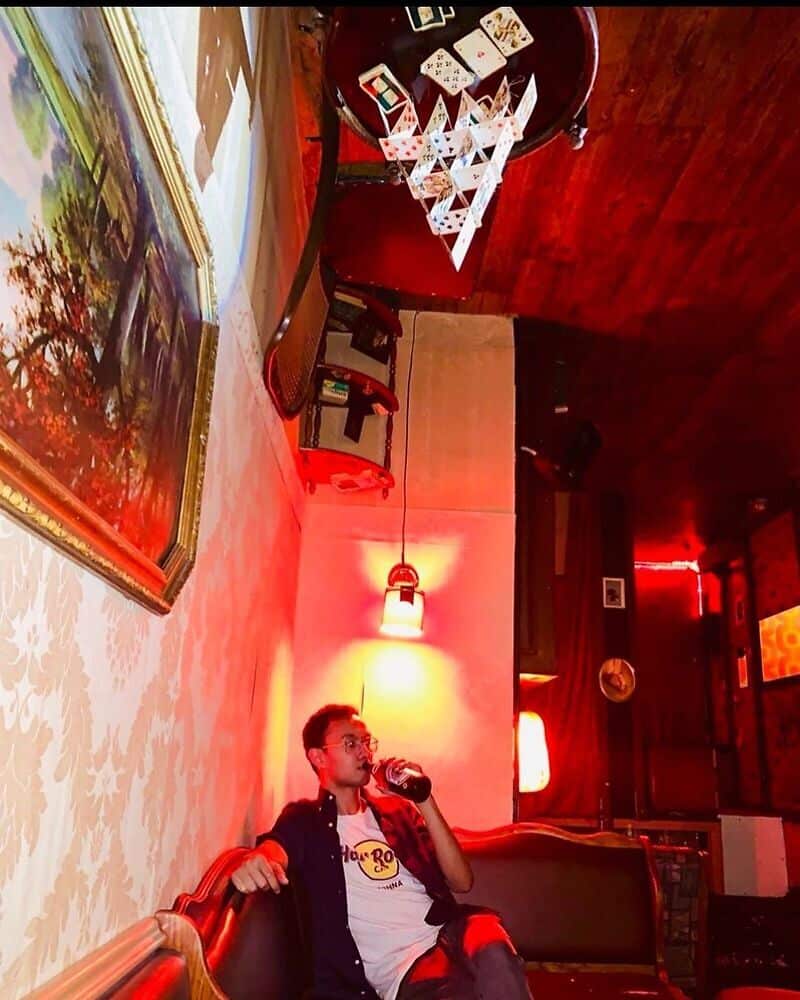 Man sitting in a bar, with furniture on the ceiling 